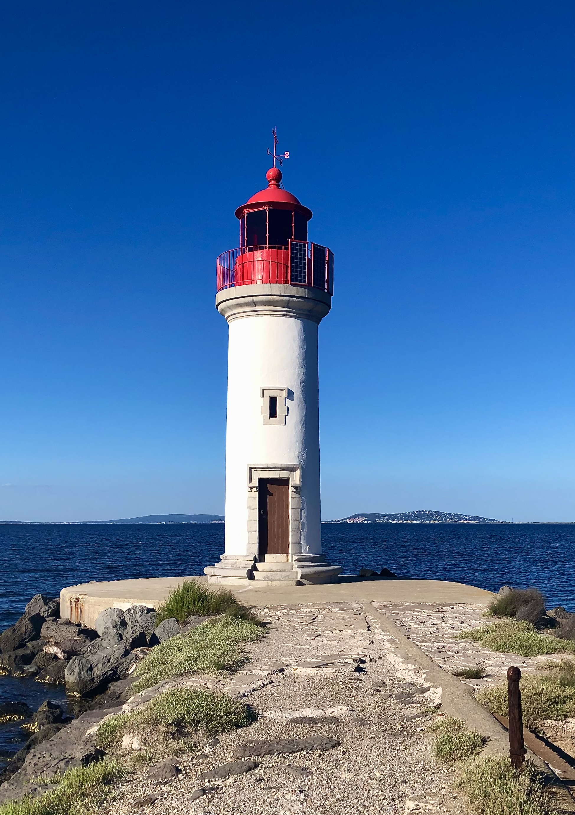Le phare des Onglous, tour blanche à lanterne rouge, à la pointe de la jetée où le canal du Midi rejoint l'étang de Thau à Marseillan.
